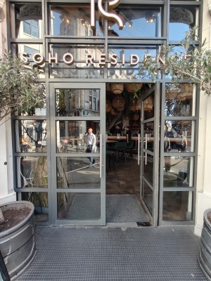 Facing grey framed double glass doors. Push silver metal vertical handles in centre to open.
