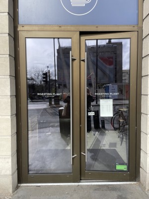 Double glass door, with brown doorframe. Handles at center. Push to open.