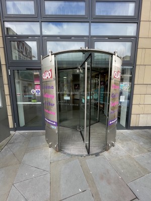 I’m the centre there is a revolving door that is to be pushed towards the right to revolve. To the left there is an accessible door with a push button to the left.