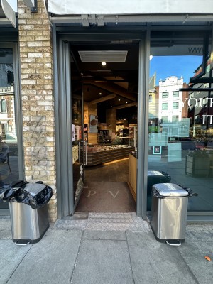 Facing grey framed glass door. Push silver metal handle on right to open.
