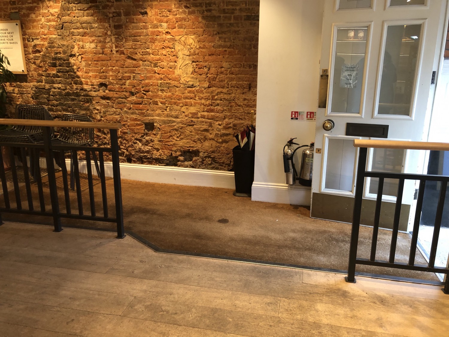 Interior side-on photo of entrance, with long shallow interior ramp carpeted with doormat material. Step option off ramp to the side