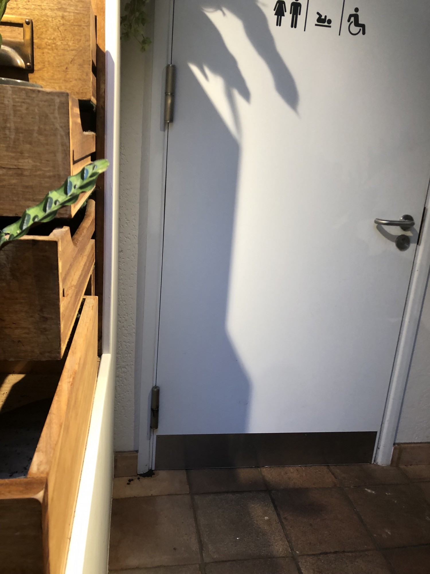 Entrance door to bathroom which would be wheelchair accessible if entrance were not blocked with tables and chairs