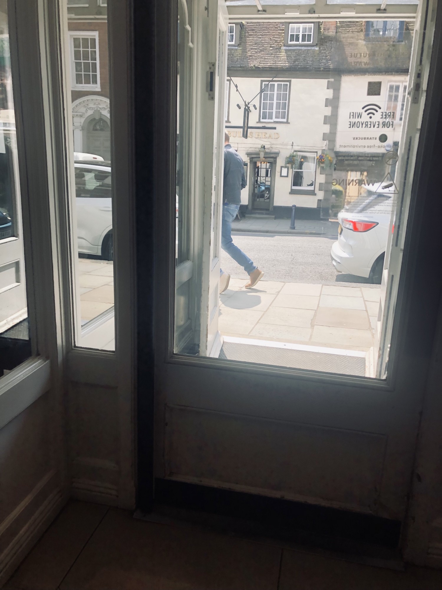 Interior photo of interior door, looking out towards street. Door has white wood frame and windows.