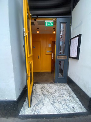 Glass door, with grey doorframe. Silver handle on right. Pull to open.