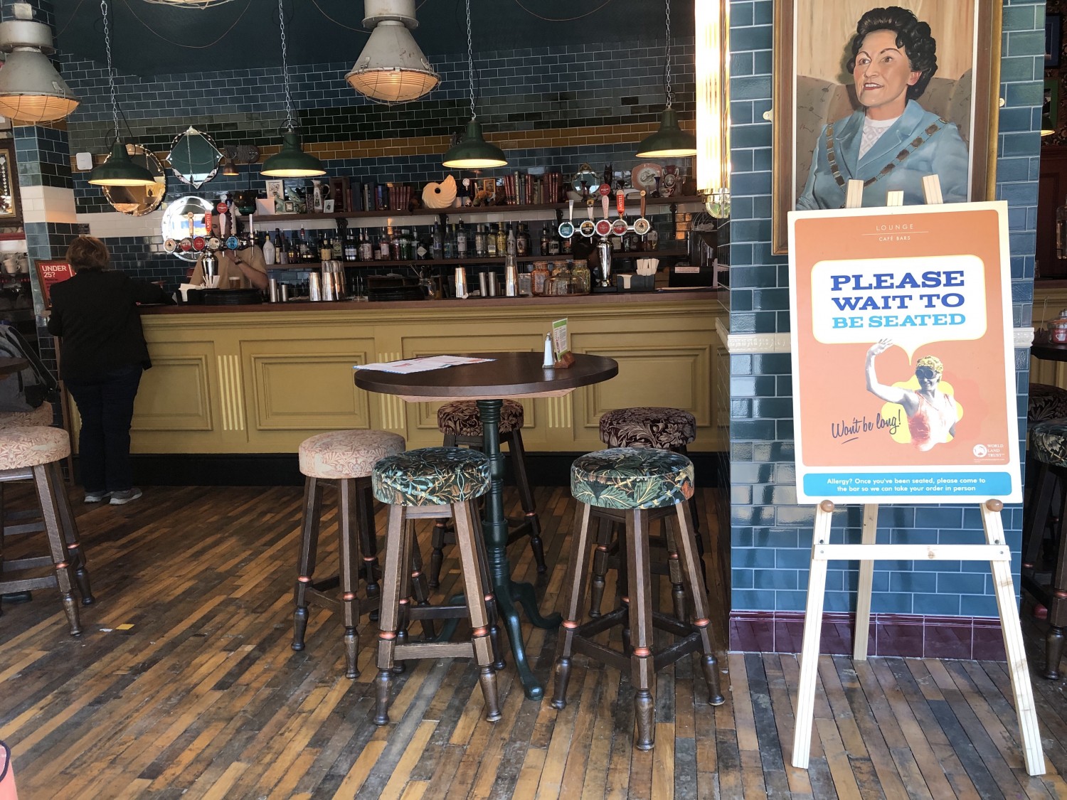 Bar and barstools around high table. Wooden flooring.