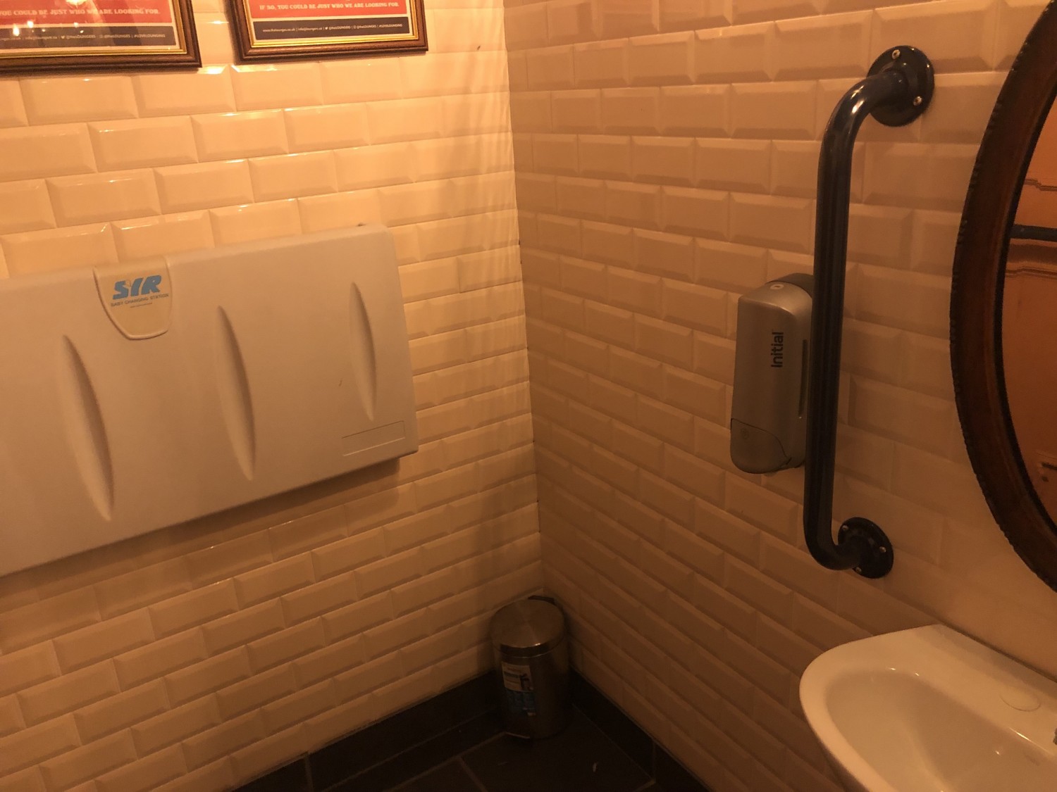 Baby changing table folded up on wall in accessible bathroom.