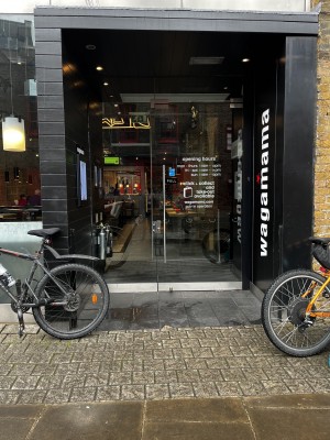 View of main entrance situated on right of venue front. Glass door that pulls open using vertical handle on left side of door.