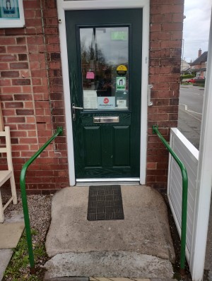 Main entrance with built-in ramp and hand rails on both sides. You have to push the door open to the right. There is a very small step after the door.