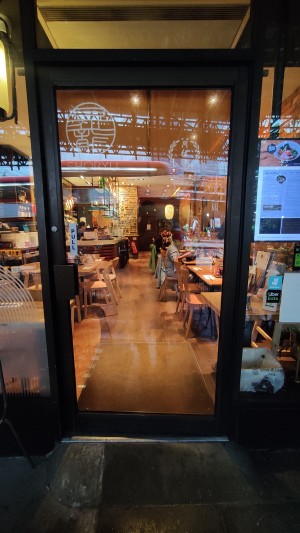 Glass door with black frames ahead. Pull via handle to left to open.