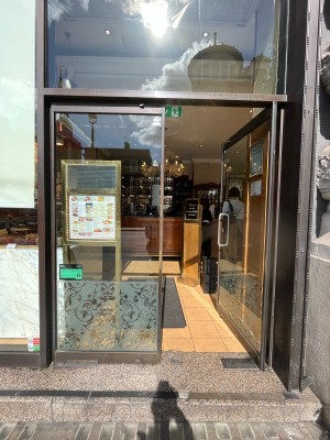 Single glass door in gold metal frame. Push silver metal handle from left to open.