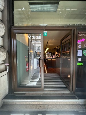 Double glass doors with brown metal frame. Push brown metal handle from centre to open.