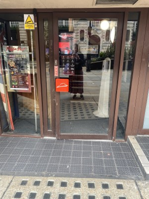First door of the main entrance. Big glass door with door handle on left side at seated height. Pull door outwards to enter.