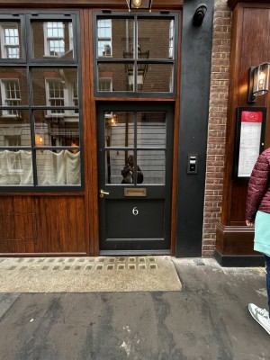 Photo of main entrance door, horizontal handle on left side of door. Push to open.