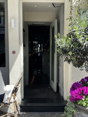 One step leading up to single door, which can be pulled open from the left via a vertical handle. Small bump at foot of door.