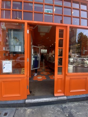 Orange wooden door with glass panels ahead. Push gold handle on right to open.