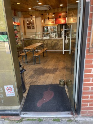 Glass door with silver handle on left. Push to open.