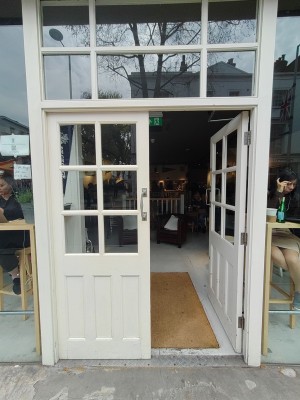Glass doors with white wooden frame. Push silver handles in centre to open.