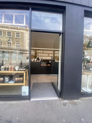 Glass door with black frames. Push metal handle on left to open.