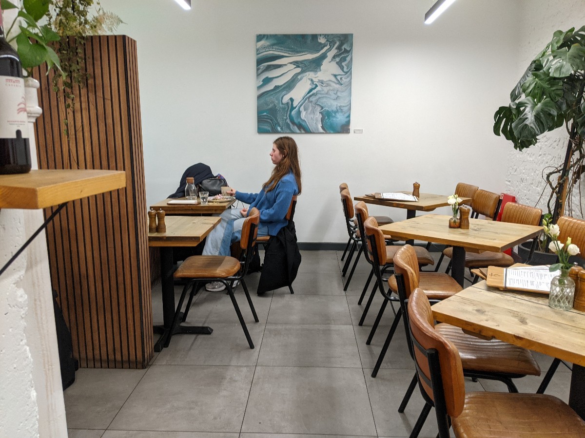 From end of counter facing straight. Tables with chairs along right. Path to downstairs area and bathroom in centre. Booth and half booth on left.