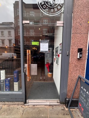 Glass door with grey frame ahead. Push wooden handle at center left to open.