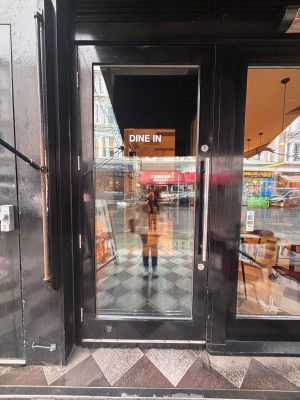 Glass door with black wooden frame ahead. Pull metal handle at center right to open.