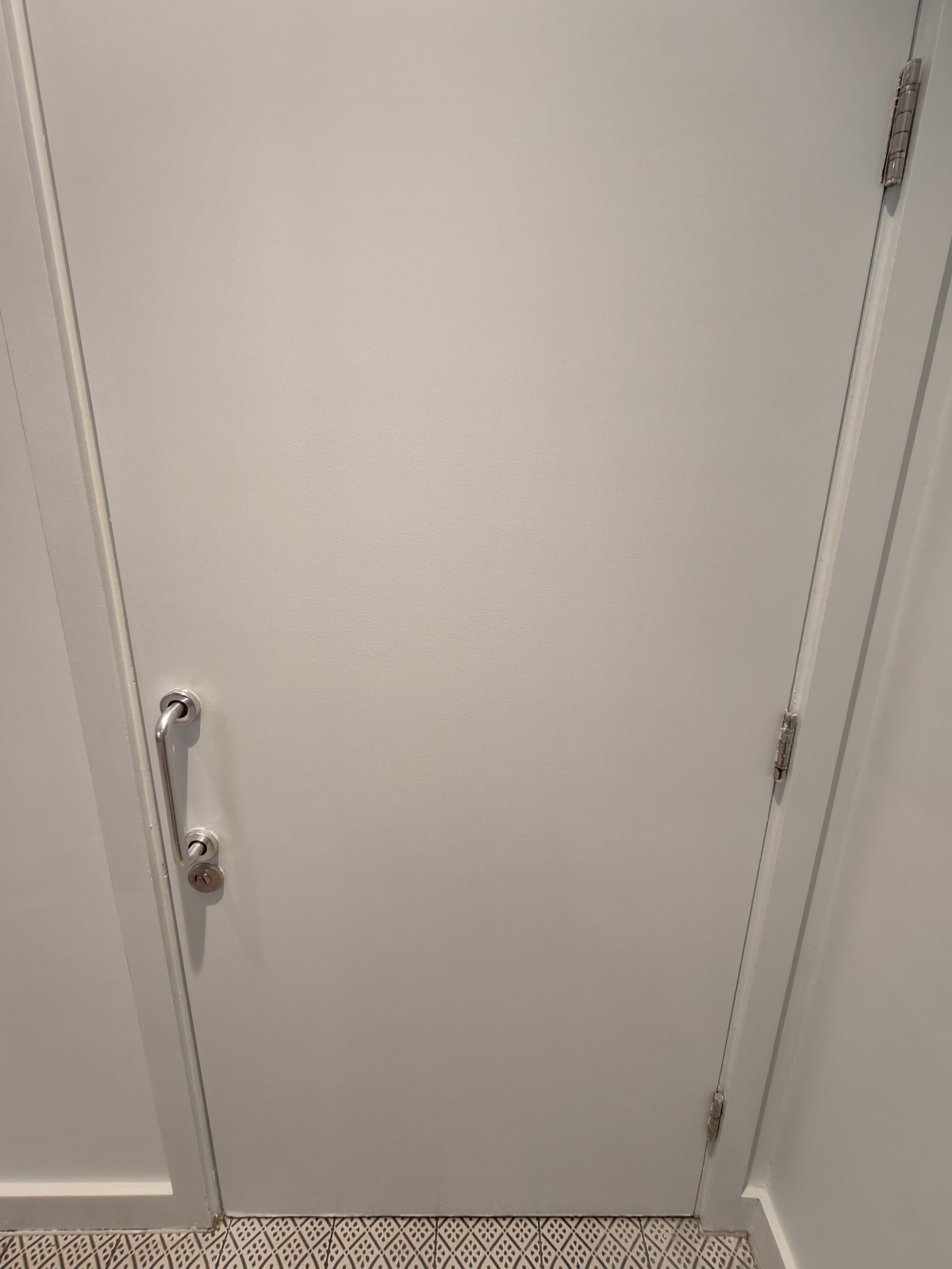 From end of path facing left. White toilet door ahead. Pull silver handle on left to open.