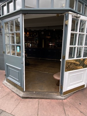 Main entrance is grey framed pull glass door, with door handle on left side of door.