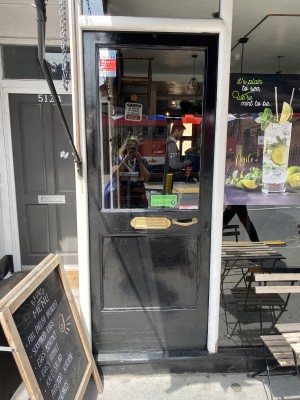 Black glass push door with white frame. Door handle on right side of door. Push to open.