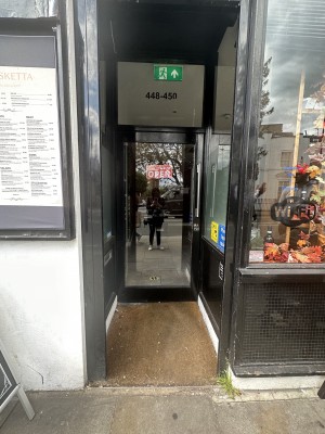 Main entrance. Preceding curtain door, followed by glass door with handle on the right side. Pull.