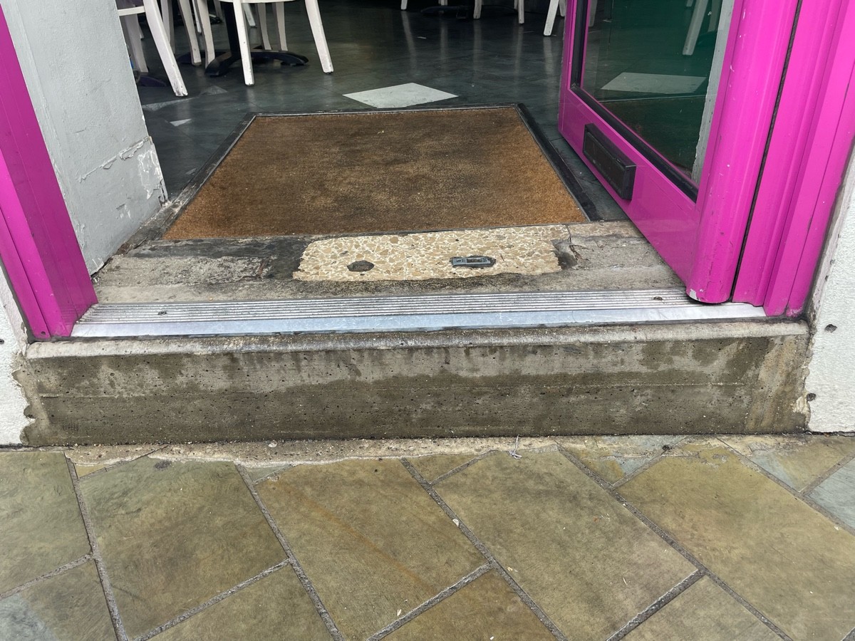 One large step up at threshold of door. Metal bump on top of step. Doormat after door.