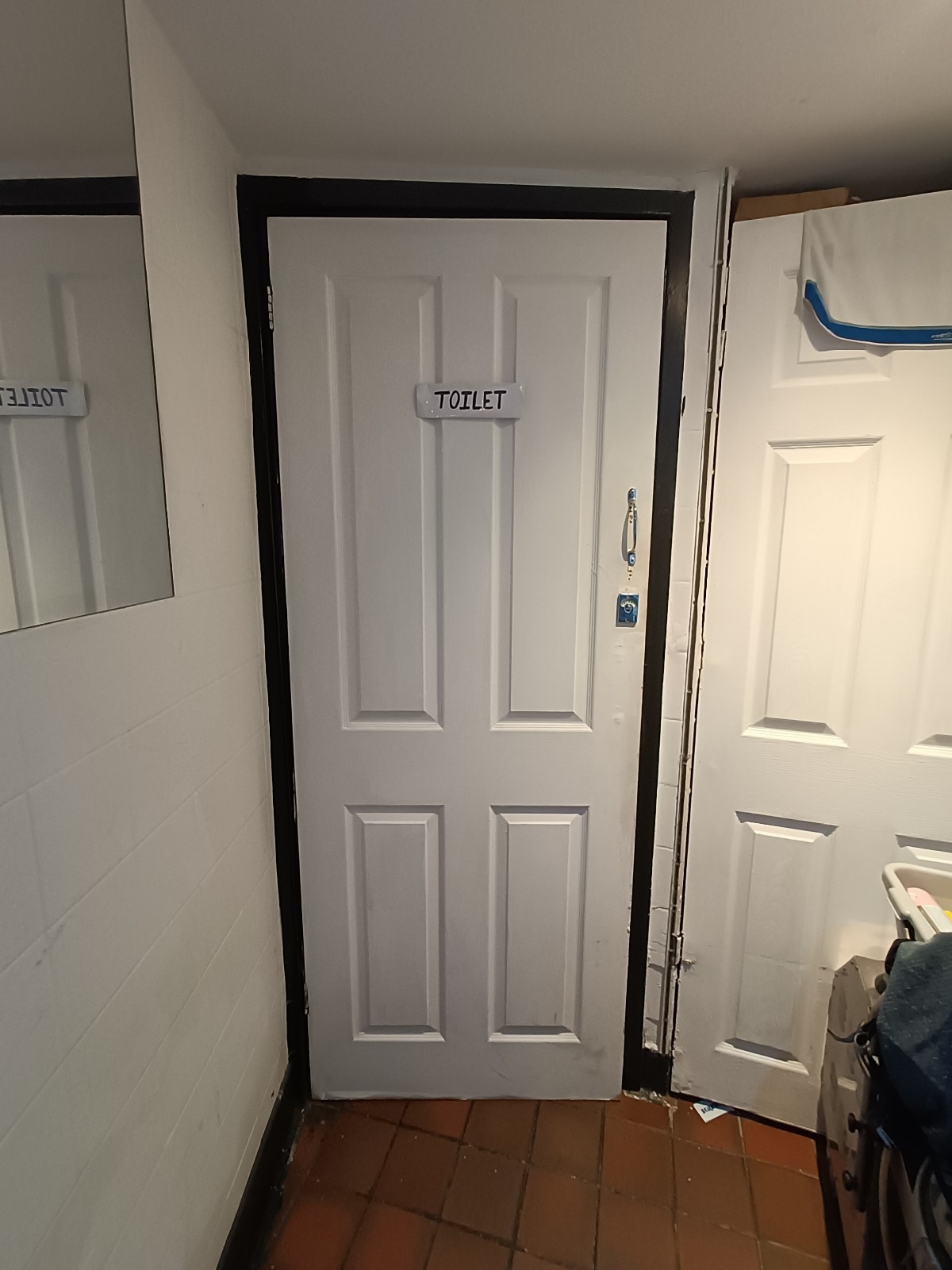 From end of path, looking straight. White, wooden bathroom door ahead. Golden, metal handle on right. Pull to open.