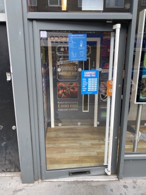 Metal-framed glass door ahead. Push white vertical handle on right to open.