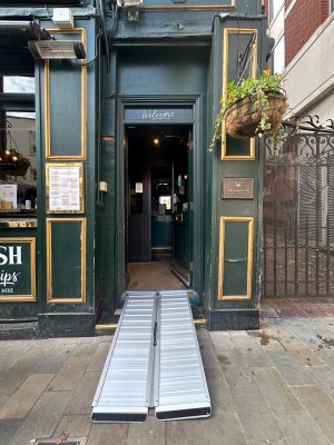 Single dark green wooden door with large glass panel and gold metal pad on left. Push to open. Ramp upon request to get up to door.