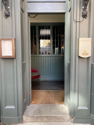 Access via single glass door with green frame. Push open via metal pad on right.