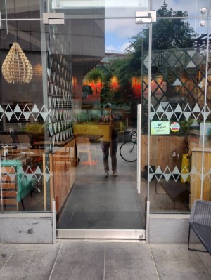 Main entrance. Glass door. Push open to the left, handle on the right. Small bump at entrance.