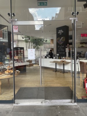 Metal-framed glass doors ahead. Push vertical silver handle at centre to open.