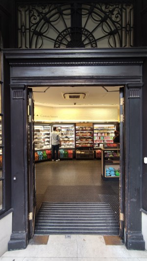 Glass doors with wooden frames ahead. Push in centre by brass handles to open.