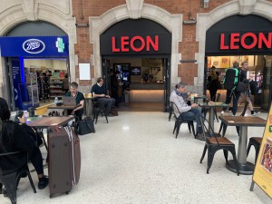 From street looking at venue from left side, seating to left and right with wide pathway in centre. Condiments counter straight ahead inside venue  through wide open doorway.
