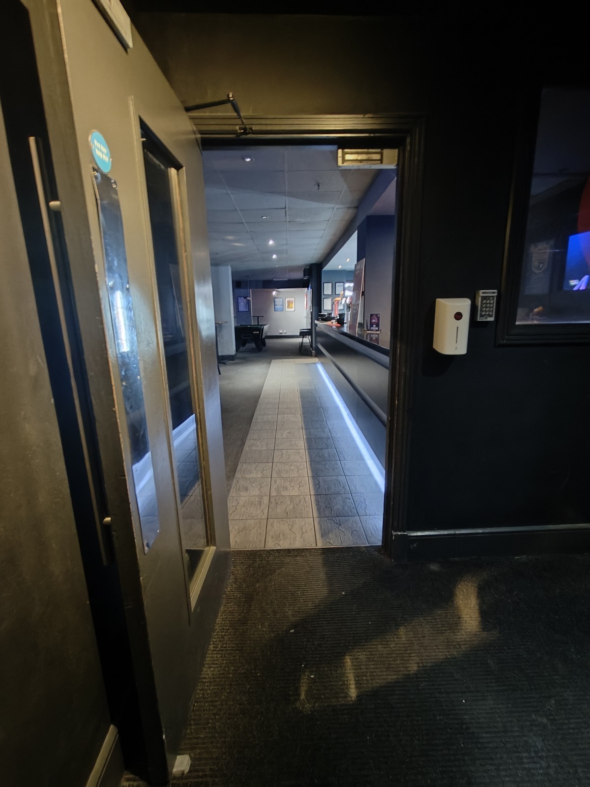 From end of path facing right. Grey framed glass panel door ahead. Pull silver handle on right to open.