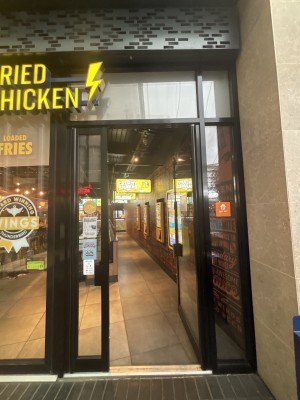 Glass door with black frame ahead. Push door via handle on left to open.
