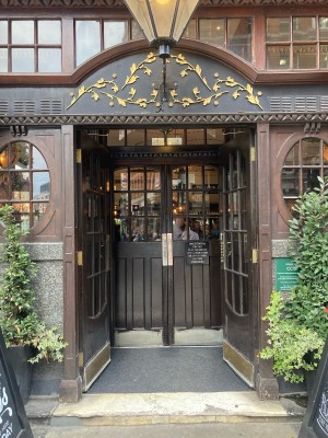 Access via double glass door with wooden frame. Push open via metal pads in center.