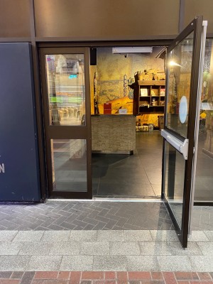 Glass door with wooden frame ahead. Pull from left to open.