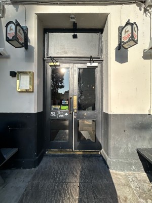 Double glass doors with black wooden frame. Gold doorknob in middle, pull to open.