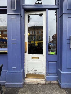 Single white wooden door with gold metal pad on left. Push to open.