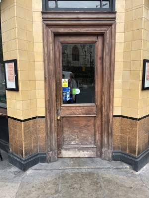 Small step leading up to a single door at the main entrance. Door pushes open from the left.