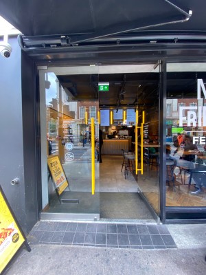 View of main entrance looking straight ahead from pavement. Handles in the middle. Push to open.
