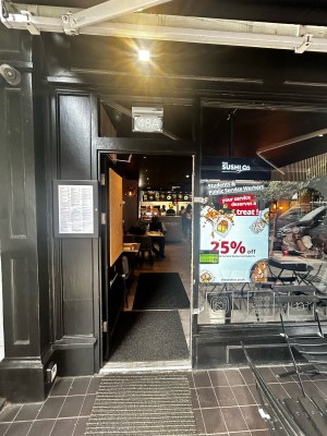 Single glass door with black frames. Silver handle on mid right. Push to open.