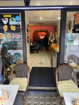 Black framed glass pull door (handle on left). One step along front. Entrance partially obstructed by seating on left and right.