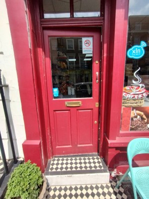 Main entrance. Wooden door with glass panel. Push open to the left. Step at door.