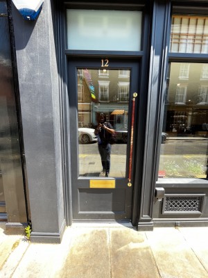 Main entrance. Long vertical handle on right of door. Push to open.